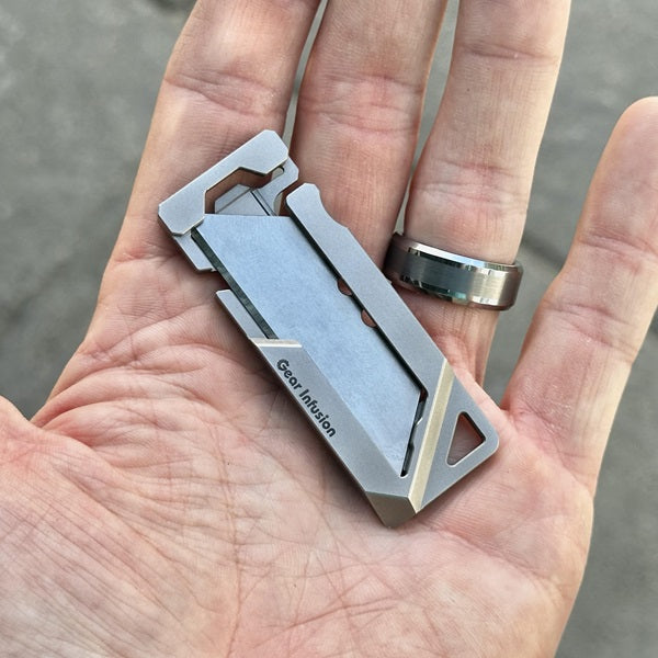 GhostTi gravity utility knife, ultra-thin and lightweight, machined from a single piece of titanium with a tool-free blade swap and dual-locking mechanism for EDC use.