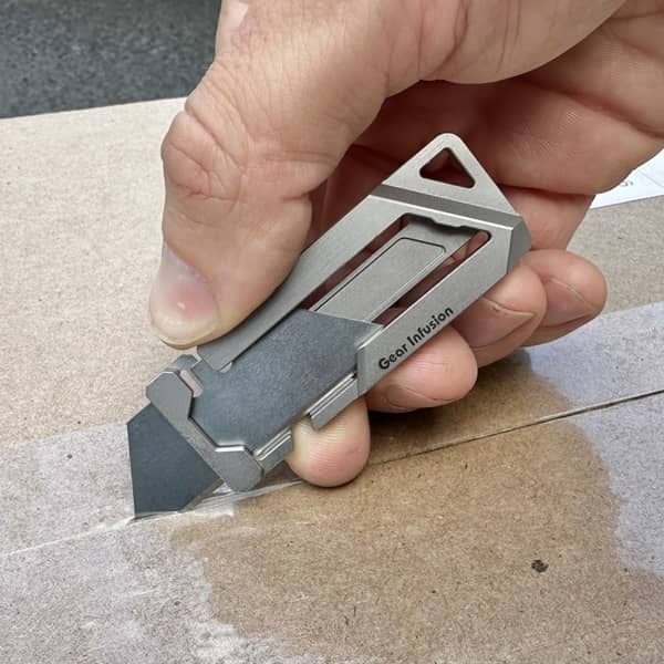 GhostTi utility knife, ultra-thin and lightweight, machined from a single piece of titanium with a tool-free blade swap and dual-locking mechanism for EDC use.